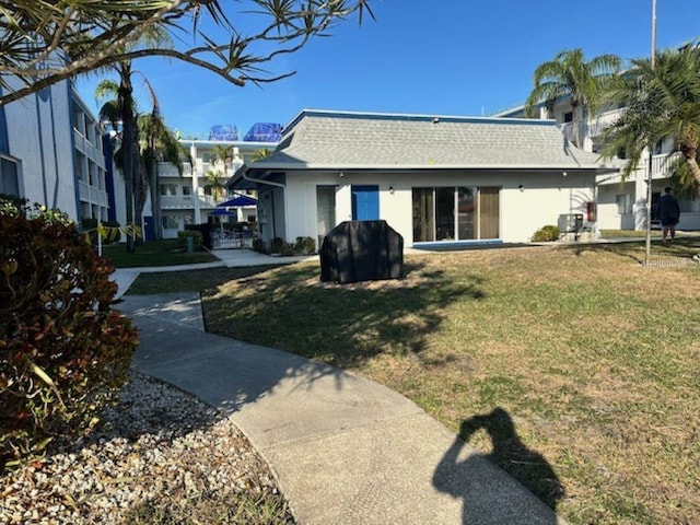 rear view of property with a residential view, roof with shingles, a yard, and stucco siding