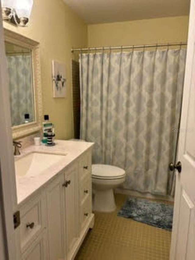 bathroom featuring toilet, tile patterned flooring, shower / tub combo with curtain, and vanity