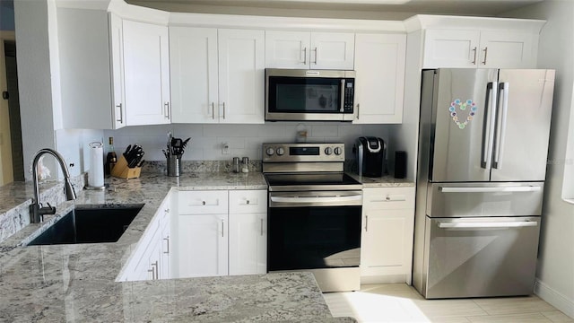 kitchen with sink, stainless steel appliances, white cabinets, and light stone countertops