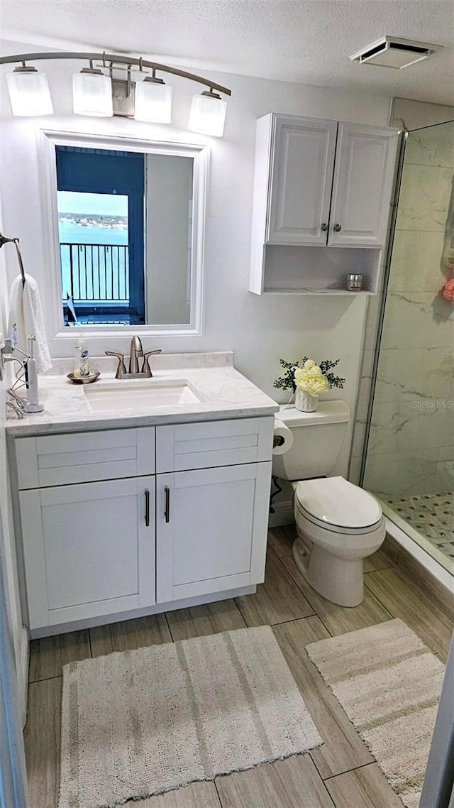 bathroom with toilet, an enclosed shower, a textured ceiling, vanity, and hardwood / wood-style flooring