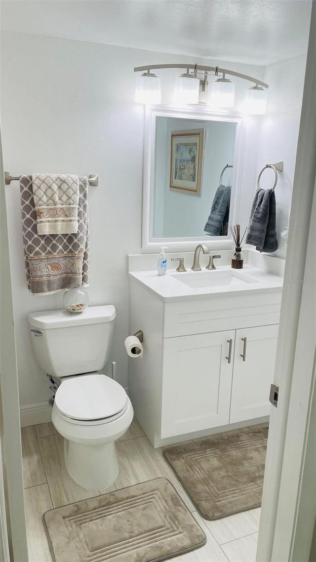 bathroom featuring vanity, a textured ceiling, and toilet