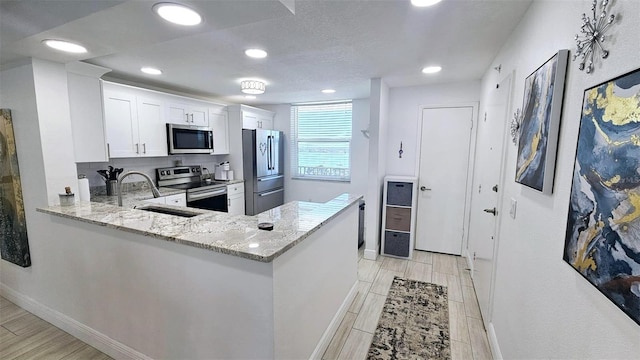 kitchen featuring wood tiled floor, light stone countertops, appliances with stainless steel finishes, and a sink