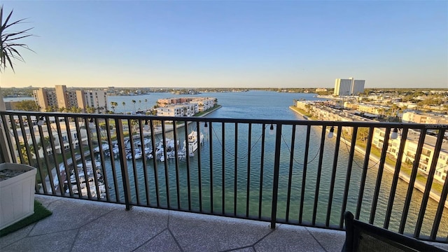 balcony with a view of city, central AC unit, and a water view