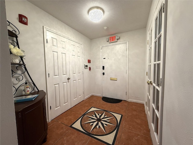 entryway with dark tile patterned flooring and a textured ceiling