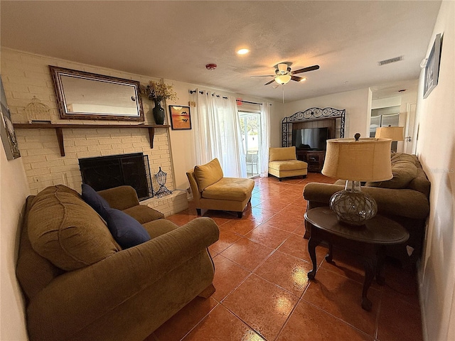 living room with ceiling fan, a textured ceiling, a fireplace, and dark tile patterned floors