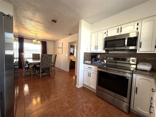 kitchen with white cabinetry, tasteful backsplash, a textured ceiling, appliances with stainless steel finishes, and dark tile patterned flooring