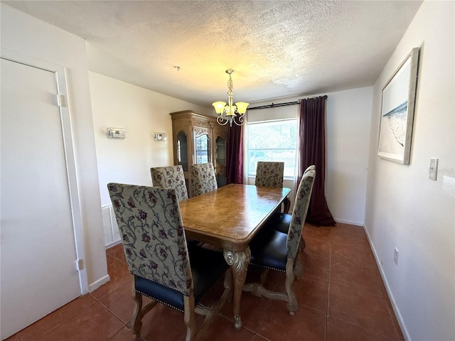 dining room with dark tile patterned floors, a notable chandelier, and a textured ceiling