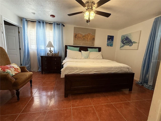 bedroom featuring dark tile patterned floors, ceiling fan, and a textured ceiling