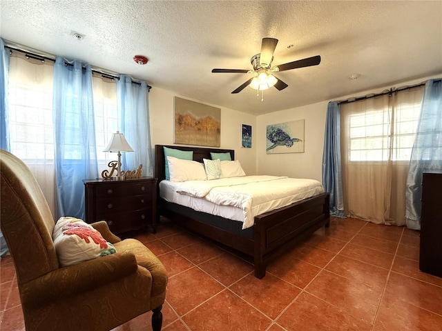 bedroom featuring a textured ceiling, dark tile patterned flooring, and ceiling fan