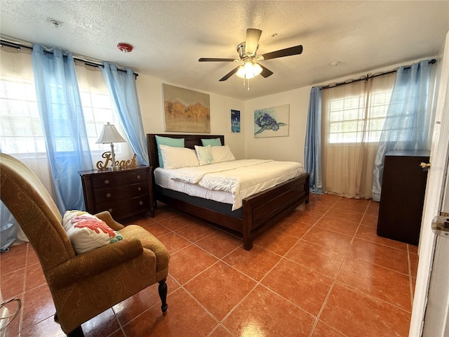 bedroom with tile patterned flooring, ceiling fan, and a textured ceiling