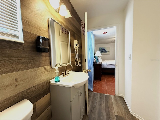 bathroom with vanity, wood-type flooring, toilet, and wood walls