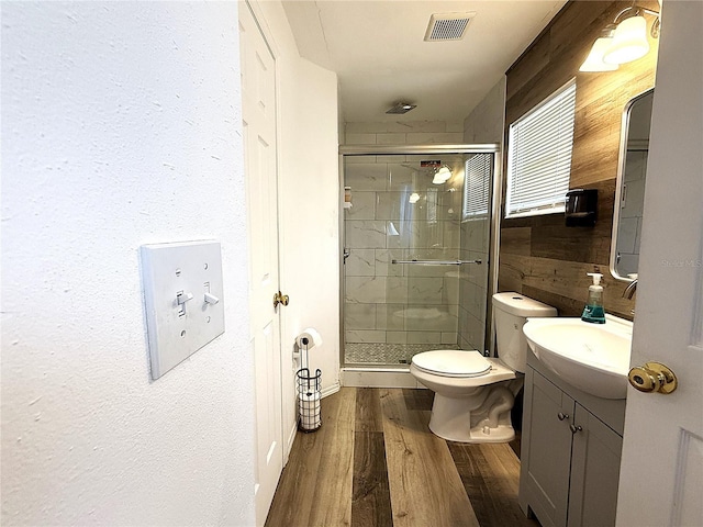 bathroom featuring vanity, wood-type flooring, a shower with shower door, and toilet