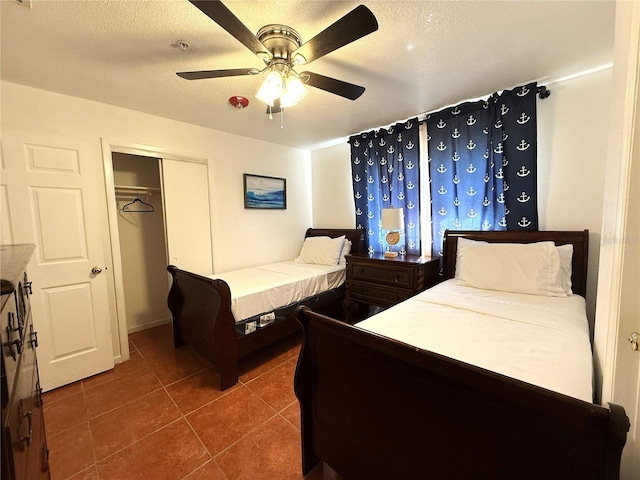 bedroom with ceiling fan, dark tile patterned flooring, a textured ceiling, and a closet