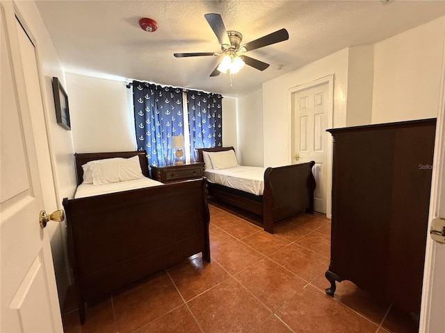 bedroom featuring dark tile patterned flooring, a textured ceiling, and ceiling fan