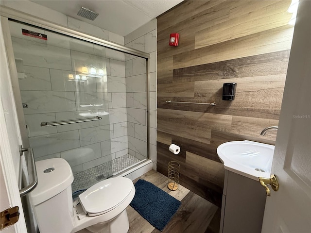 bathroom featuring vanity, an enclosed shower, wooden walls, and toilet