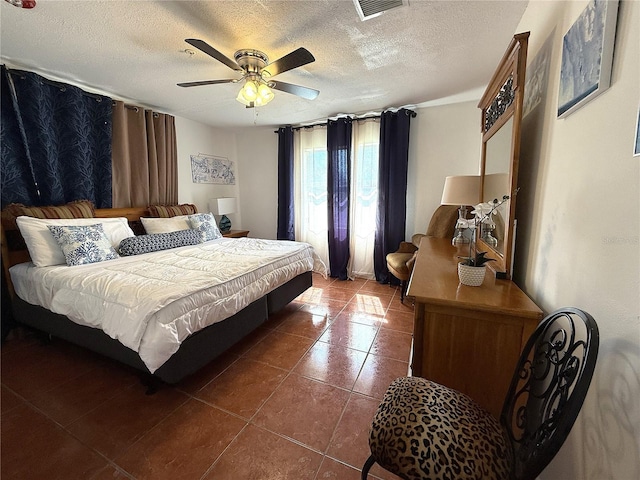 bedroom with dark tile patterned floors, ceiling fan, and a textured ceiling