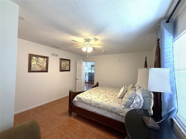 bedroom featuring ceiling fan, tile patterned floors, and a textured ceiling