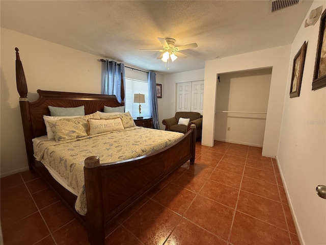 bedroom with dark tile patterned floors, ceiling fan, a textured ceiling, and a closet