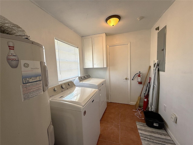 laundry area featuring dark tile patterned flooring, washer and clothes dryer, electric panel, and cabinets