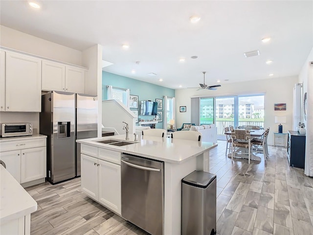 kitchen featuring white cabinetry, appliances with stainless steel finishes, sink, and a center island with sink