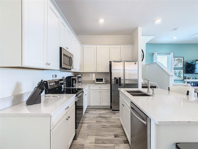 kitchen with sink, light stone counters, stainless steel appliances, light hardwood / wood-style floors, and white cabinets