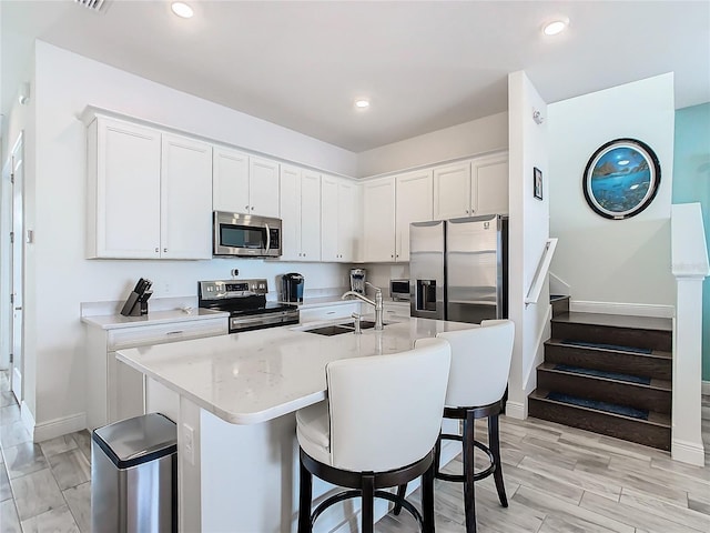 kitchen with sink, a center island with sink, white cabinets, and appliances with stainless steel finishes