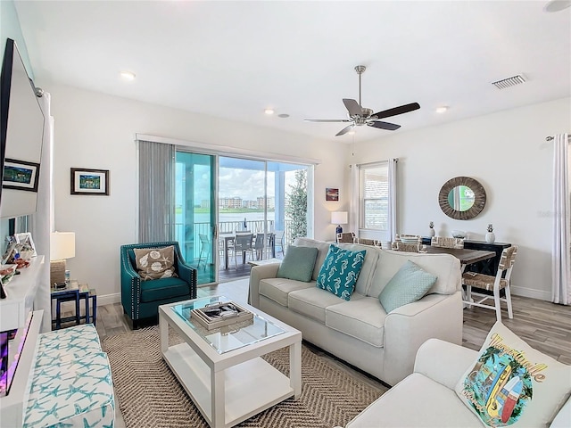 living room with ceiling fan and light hardwood / wood-style flooring