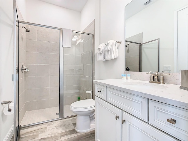 bathroom with hardwood / wood-style flooring, vanity, an enclosed shower, and toilet