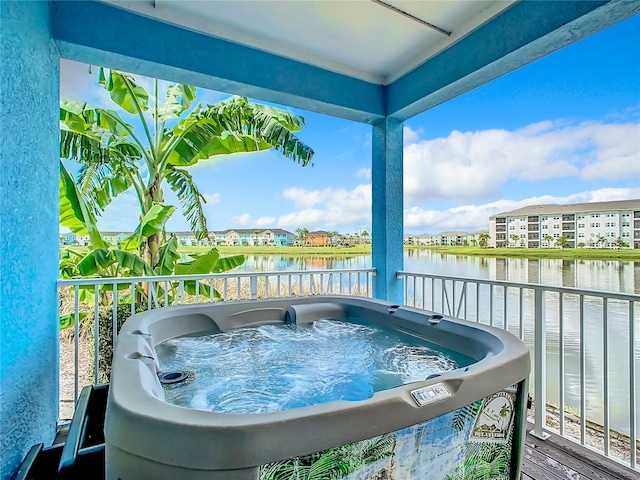 balcony with a water view and a hot tub