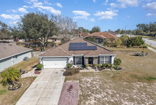 ranch-style home with a garage, a front lawn, and solar panels