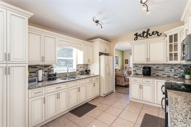 kitchen with stainless steel appliances, light stone countertops, sink, and light tile patterned floors