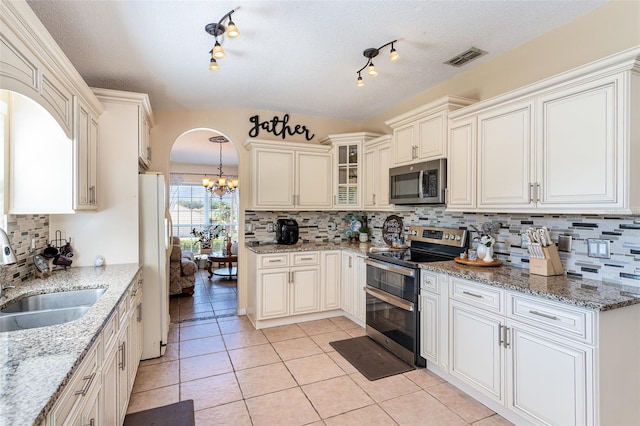 kitchen featuring light stone counters, sink, hanging light fixtures, and appliances with stainless steel finishes