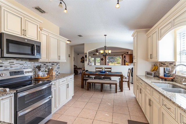 kitchen featuring light tile patterned floors, sink, hanging light fixtures, stainless steel appliances, and cream cabinetry