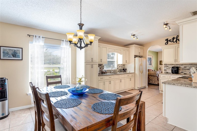 dining area featuring light tile patterned floors, a textured ceiling, and an inviting chandelier