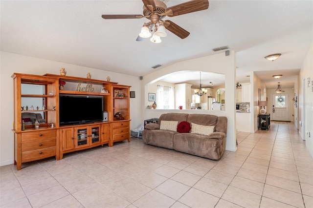 living room featuring vaulted ceiling, ceiling fan with notable chandelier, light tile patterned floors, and a textured ceiling