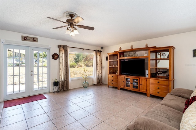 living room featuring ceiling fan, light tile patterned floors, a textured ceiling, and french doors