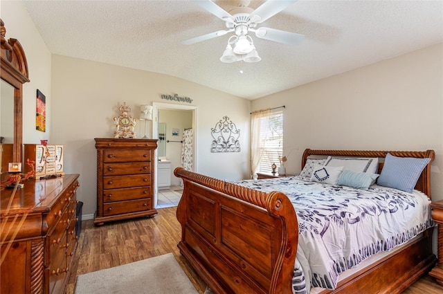 bedroom with lofted ceiling, ceiling fan, connected bathroom, a textured ceiling, and light wood-type flooring