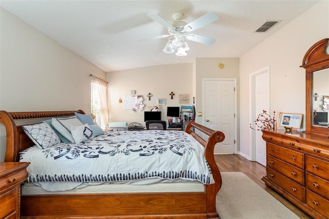 bedroom featuring ceiling fan, hardwood / wood-style floors, and a textured ceiling