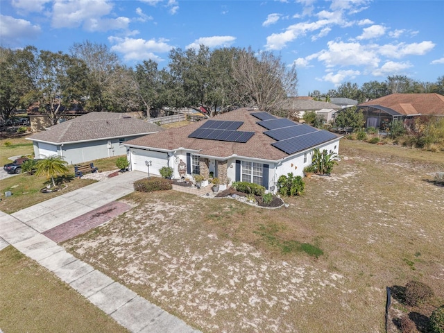 view of front facade with a garage, a front lawn, and solar panels