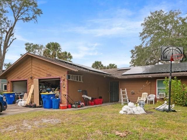 back of house featuring a lawn and solar panels