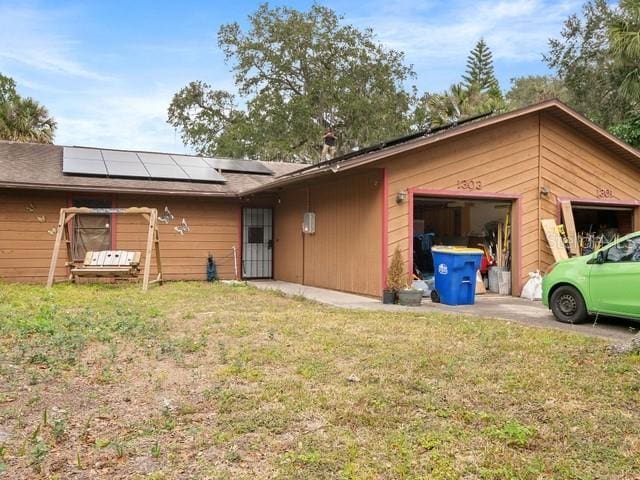 view of property exterior featuring a yard, a garage, and solar panels