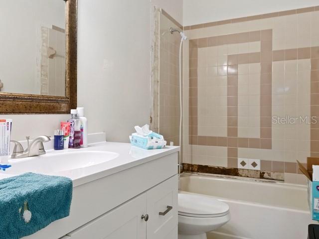 full bathroom with vanity, tiled shower / bath combo, and toilet