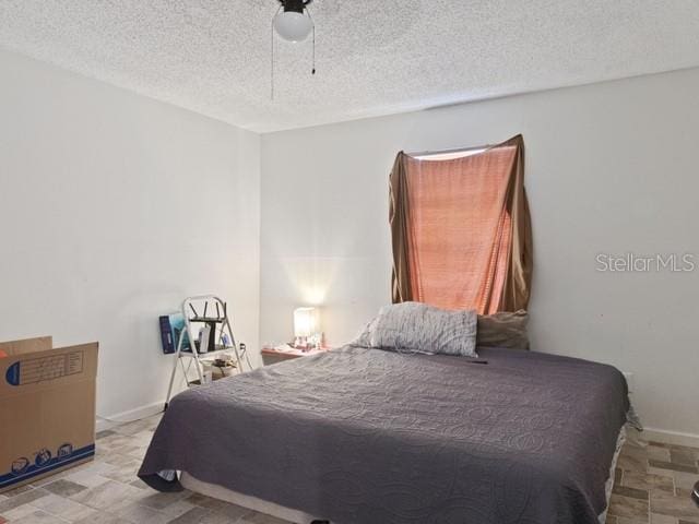 bedroom featuring ceiling fan and a textured ceiling