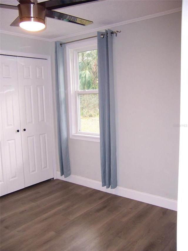 unfurnished bedroom featuring crown molding, dark wood-type flooring, ceiling fan, and a closet