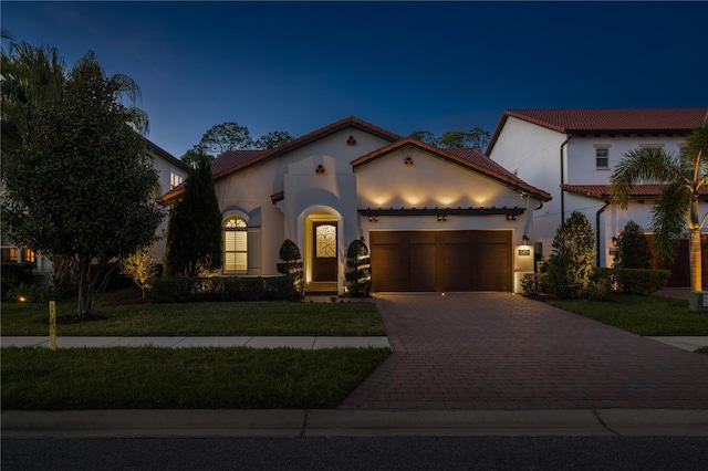 mediterranean / spanish house featuring a garage and a yard