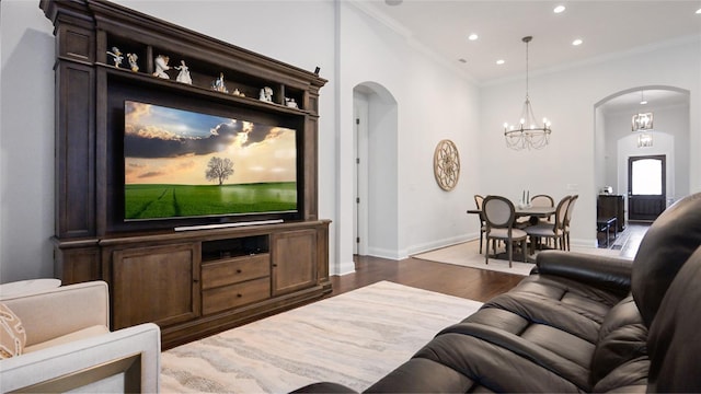 living room with dark wood-type flooring, ornamental molding, and a notable chandelier