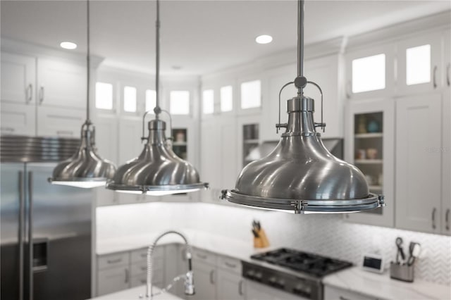 interior details with stove, decorative light fixtures, stainless steel built in fridge, and white cabinets