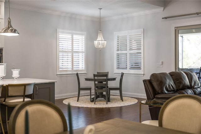 dining area with dark wood-type flooring, crown molding, and a chandelier