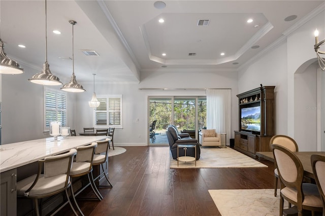 dining space with ornamental molding, wood-type flooring, and a tray ceiling