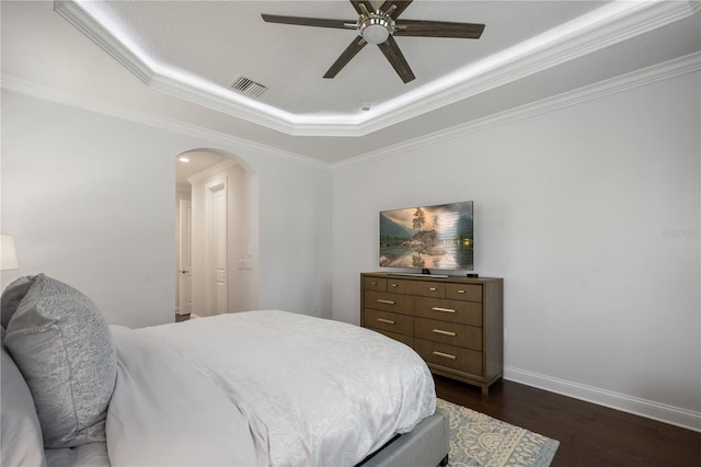 bedroom featuring crown molding, a tray ceiling, dark wood-type flooring, and ceiling fan